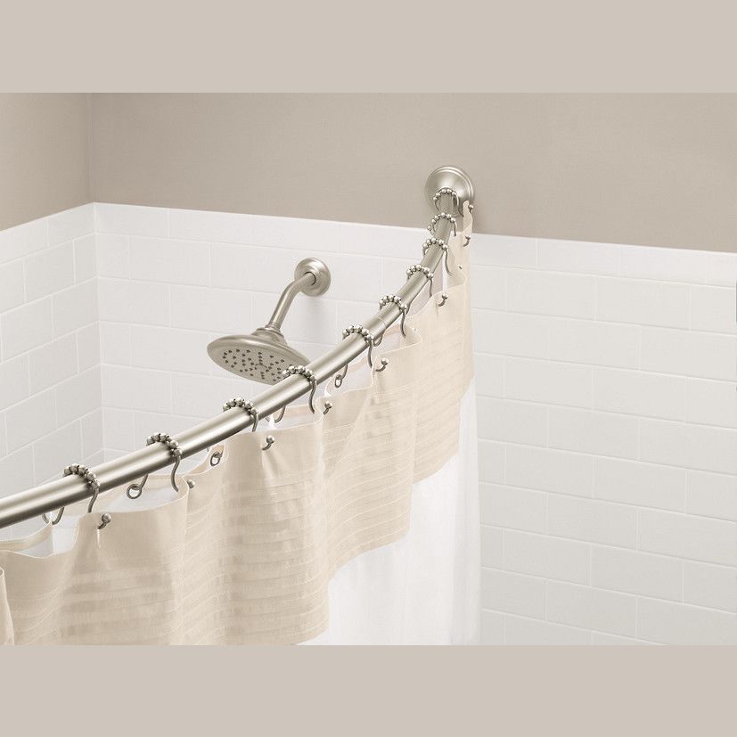 Curved brushed nickel shower curtain rod with matching rings and beige fabric curtain in bathroom setting