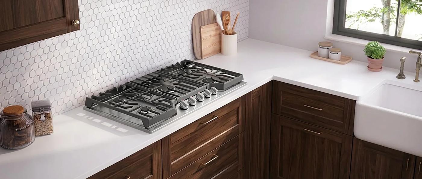 Modern stainless steel gas cooktop with five burners integrated into a kitchen countertop in home improvement setting