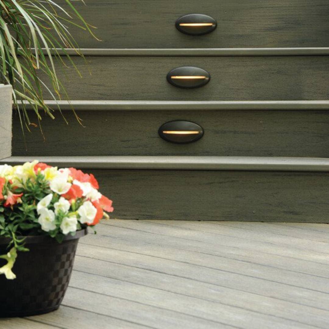 Architectural bronze LED deck riser lights installed on dark wood steps for outdoor living and deck safety enhancements