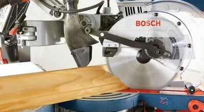 Close-up of Bosch dual-bevel miter saw cutting a wooden board, part of power tools and home improvement collections