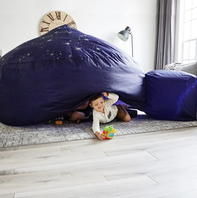 Child playing inside a navy blue AirFort with starry patterns creating a cozy indoor play space