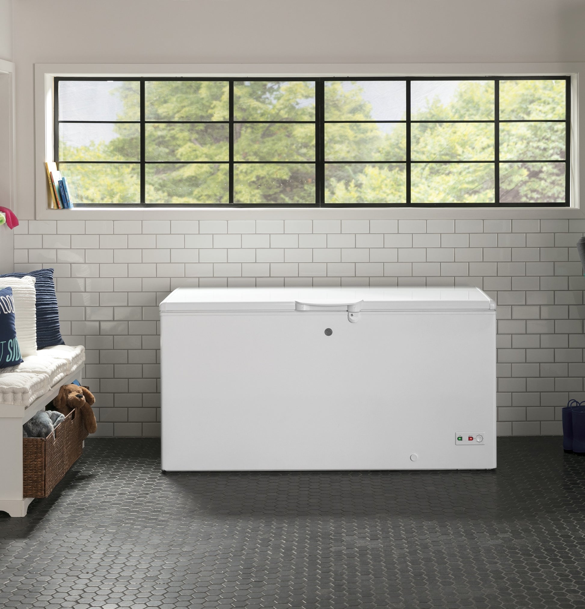 White manual defrost chest freezer with lock, control lights, and temperature dial in bright laundry room setting