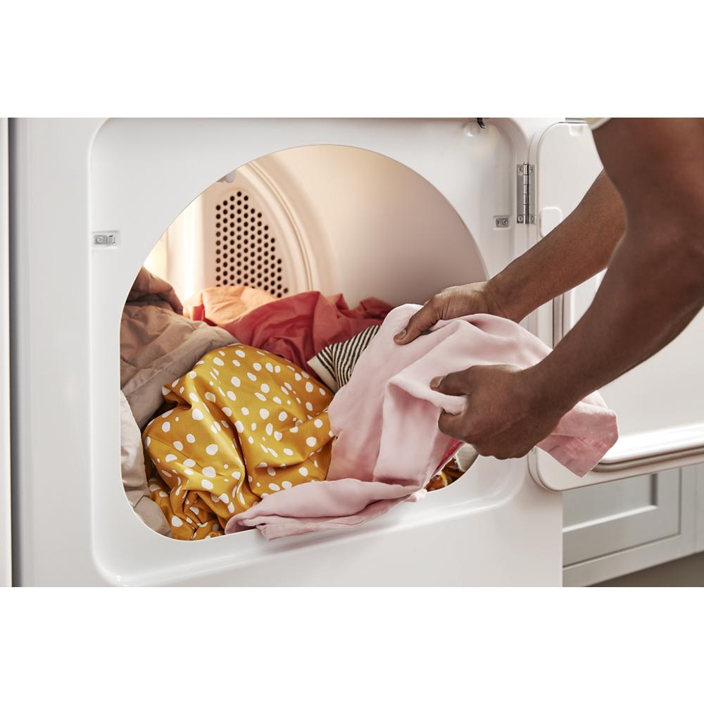 Hands removing colorful clothes from the drum of a moisture sensing dryer in the Dryers and Appliances collections