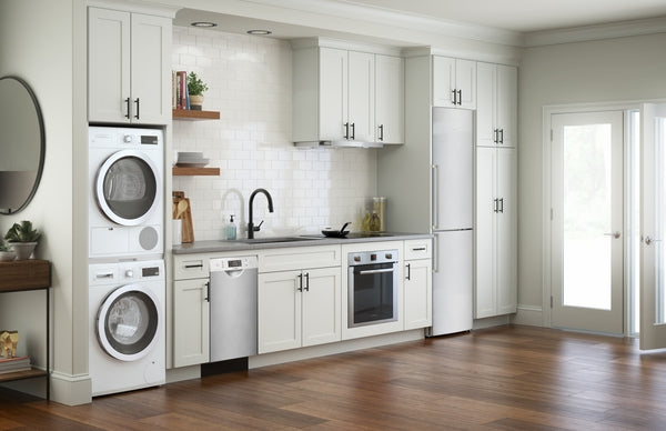 Modern kitchen featuring stainless steel single wall oven, dishwasher, refrigerator, and stacked washer-dryer units in light cabinetry