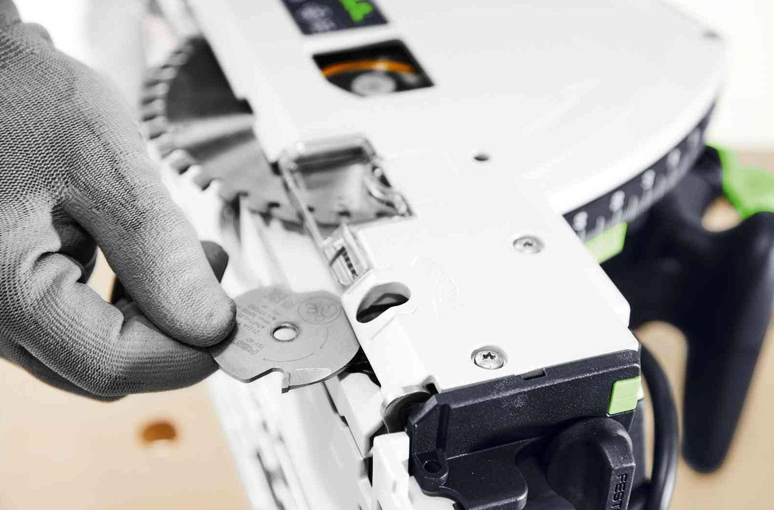 Hand wearing glove adjusting blade on white plunge cut track saw for precise power tool use in home improvement