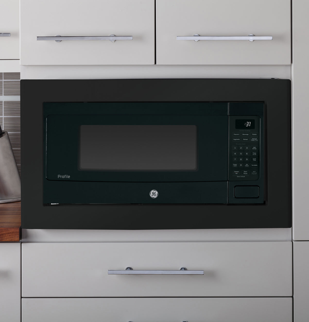 Built-in black trim kit surrounding microwave installed within white kitchen cabinetry in appliances collection