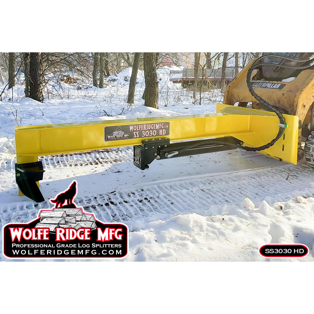 Yellow skid steer log splitter attachment connected to machine outdoors on snow-covered ground for firewood processing