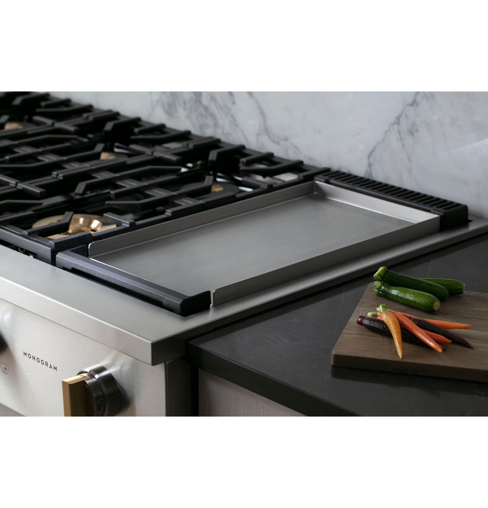 Stainless steel rangetop with six burners and built-in griddle in modern kitchen with fresh vegetables nearby