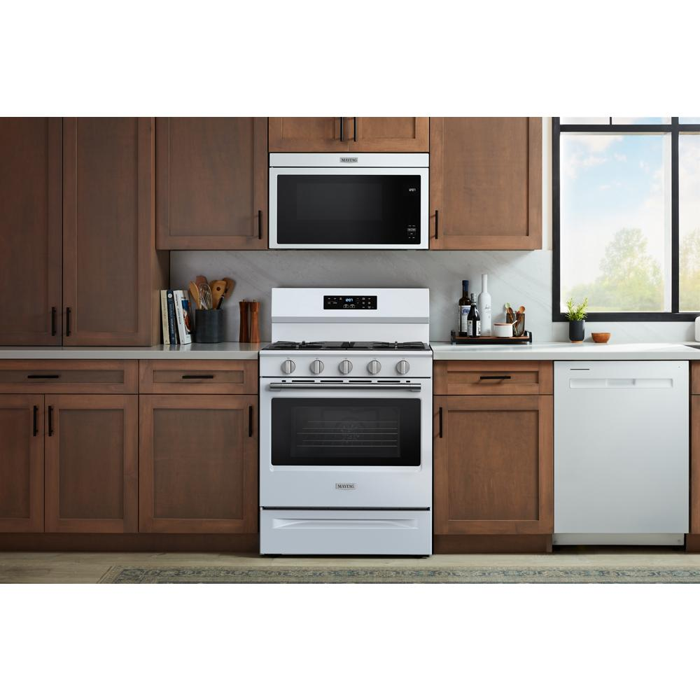 White 30-inch gas range with four burners, digital controls, and oven in modern kitchen with wooden cabinetry and appliances