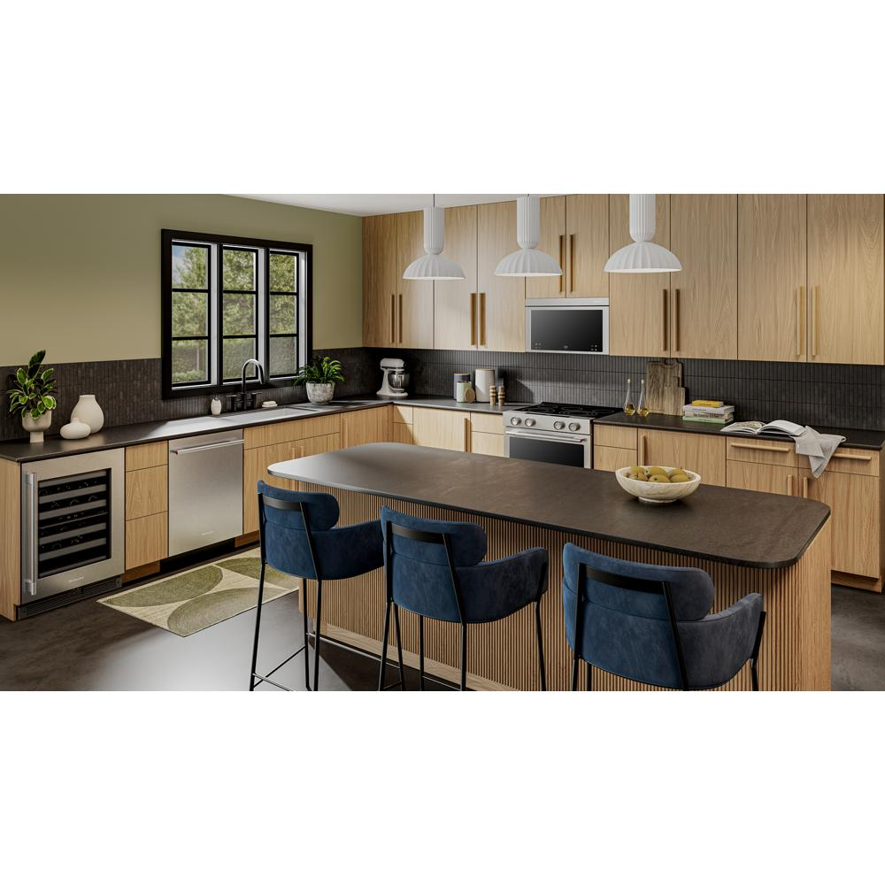 Modern kitchen featuring light wood cabinetry, undercounter beverage center, stainless steel appliances, and dark stone countertops.
