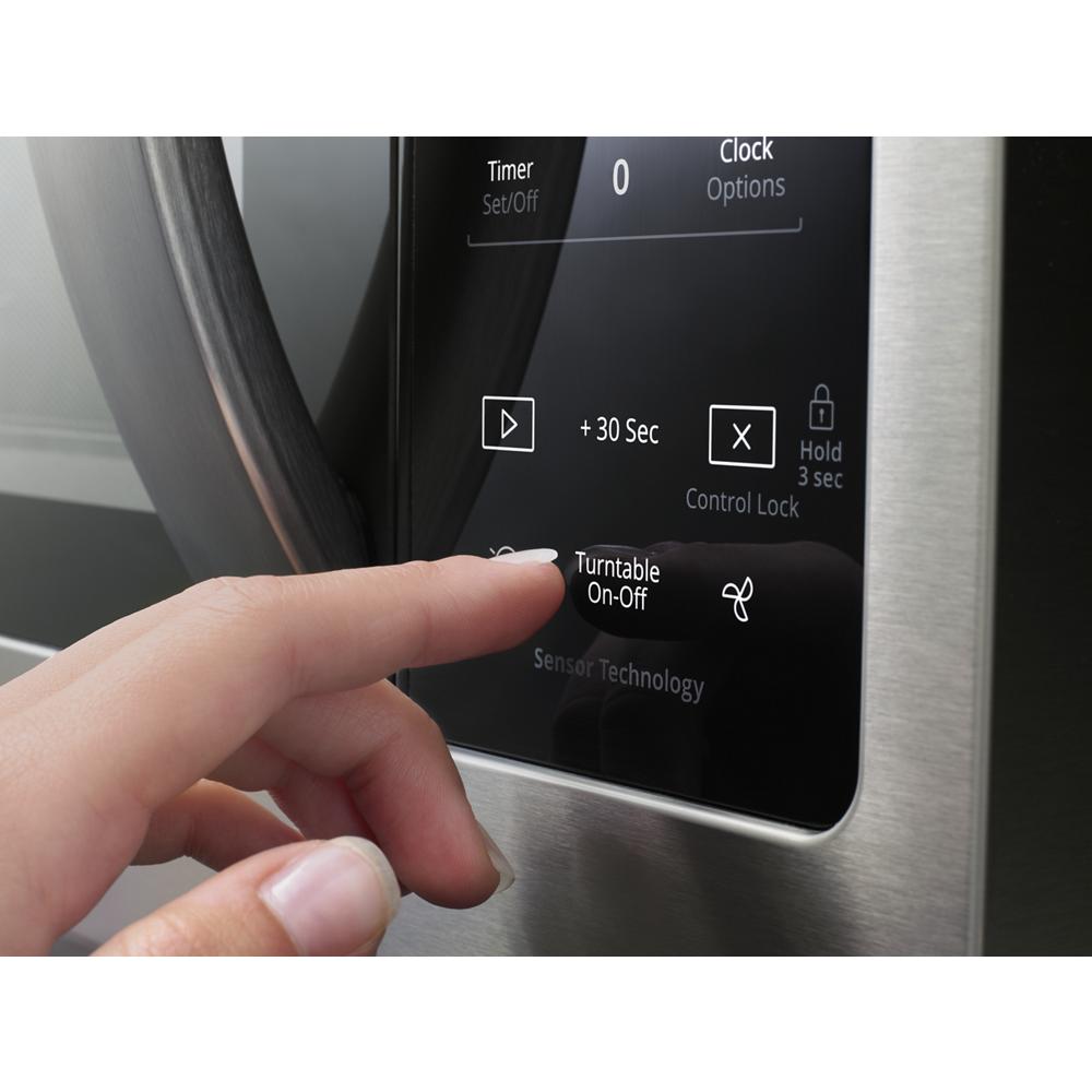 Finger pressing digital control panel button on stainless steel steam microwave from kitchen appliances category