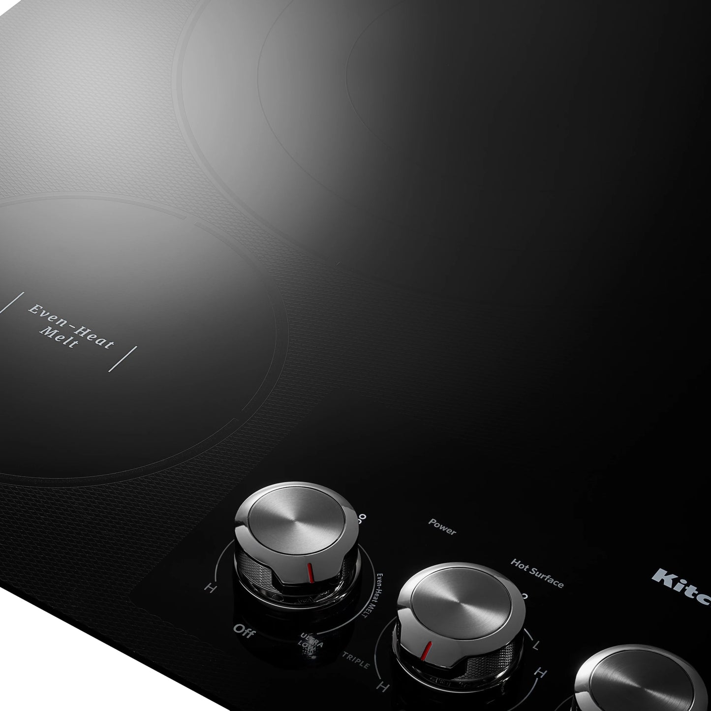 Close-up of stainless steel knob controls and radiant element labeled Even-Heat Melt on black electric cooktop surface