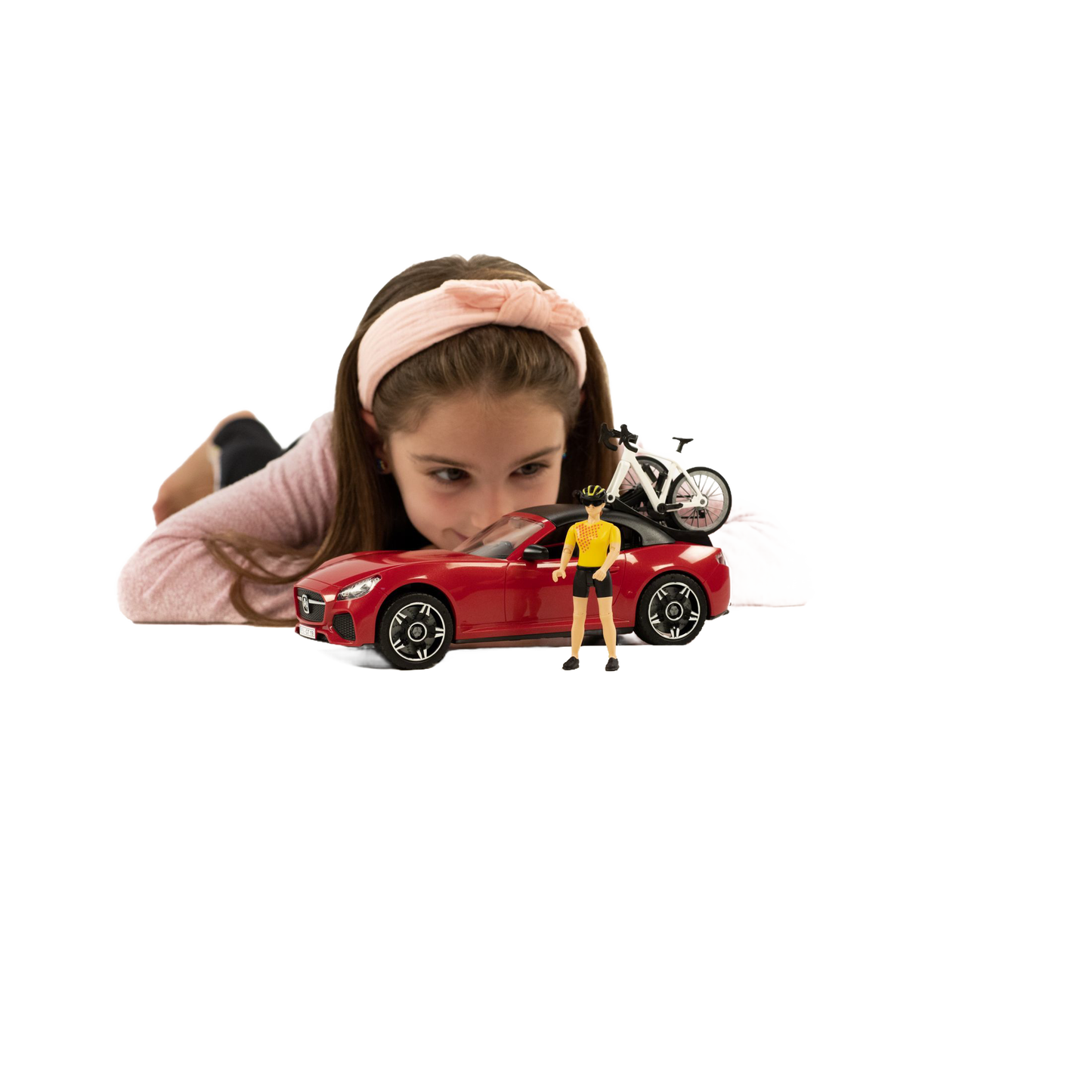 Young girl playing with red toy roadster carrying a white racing bicycle and cyclist figure for Bruder Toys collection