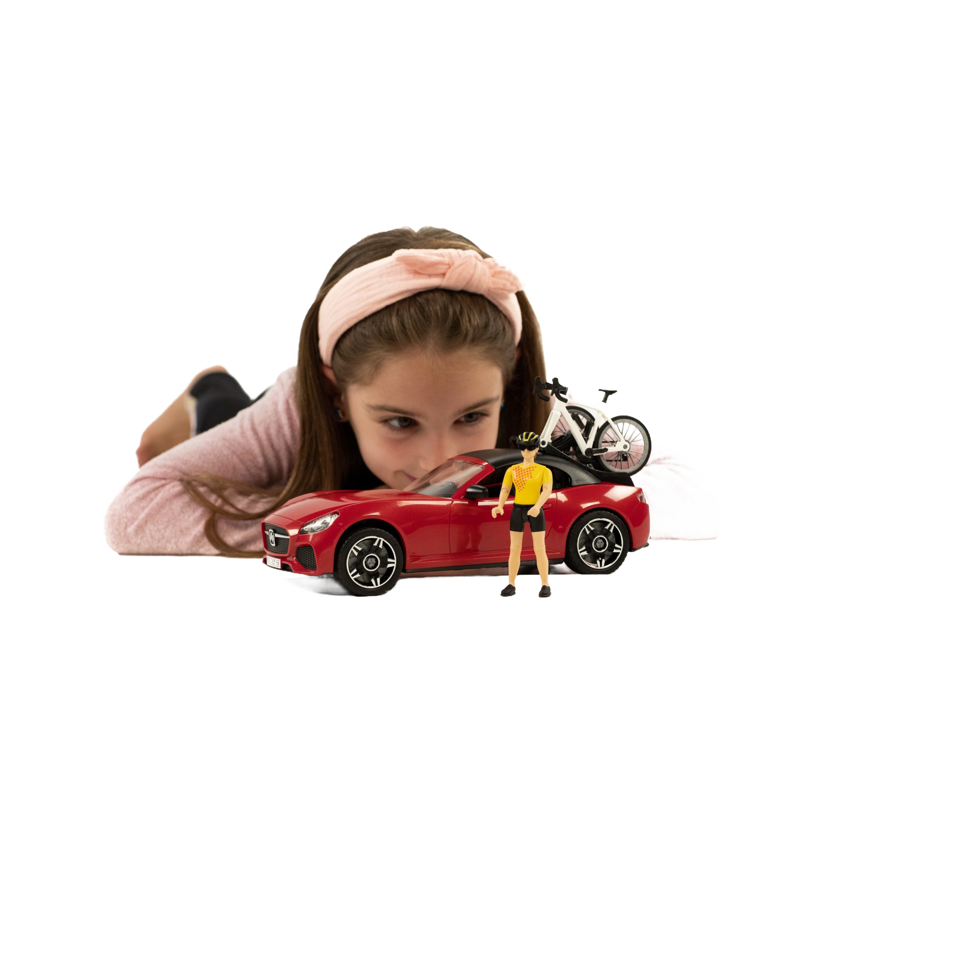 Young girl playing with red toy roadster carrying a white racing bicycle and cyclist figure for Bruder Toys collection