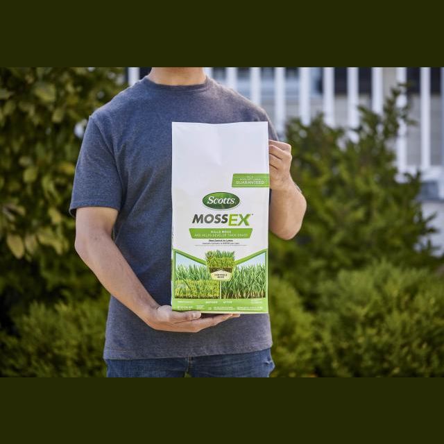 Person holding a bag of Scotts MossEX granules for lawn care and moss control in garden settings