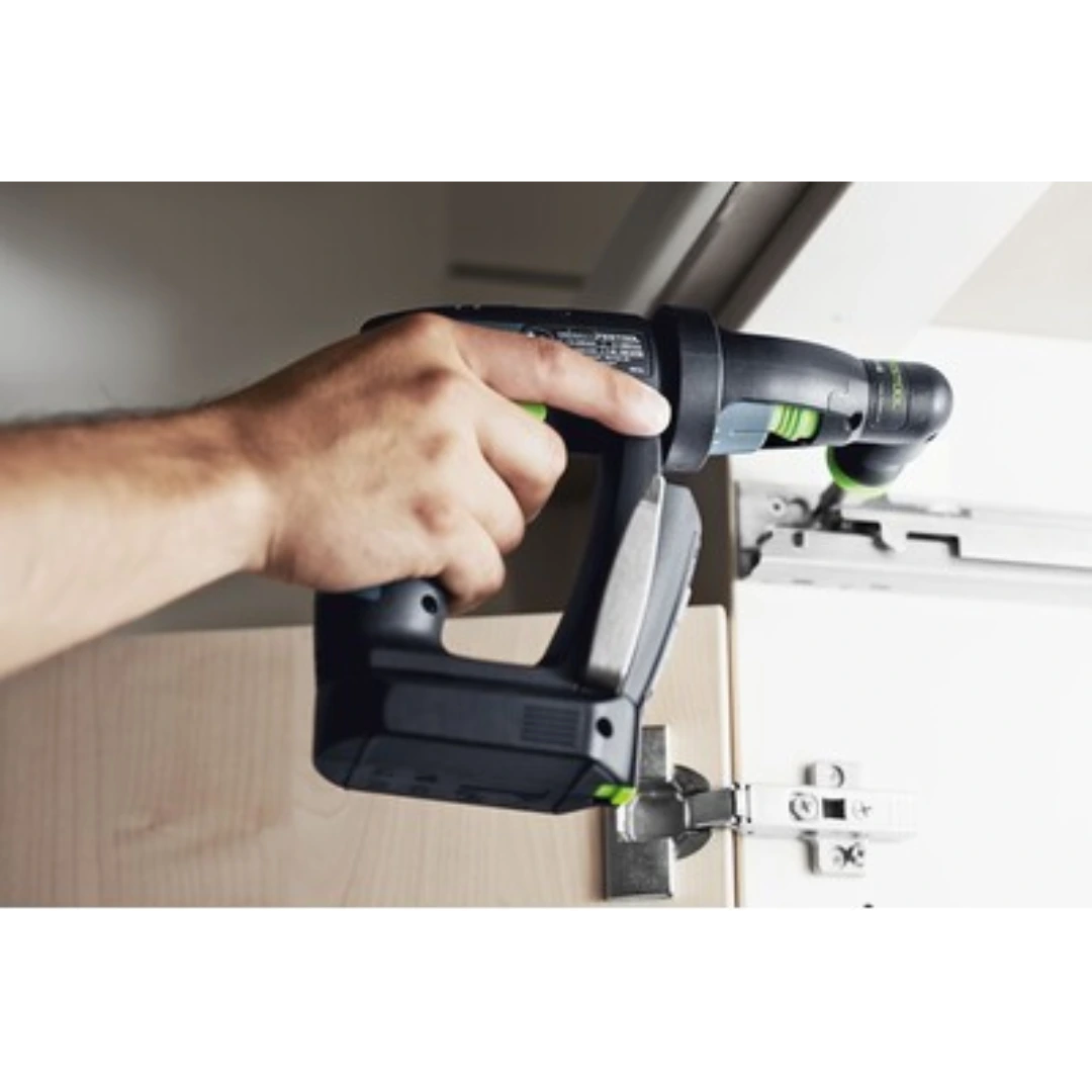Compact black and green right-angle drill attachment being used on a cabinet hinge in home improvement tools collection