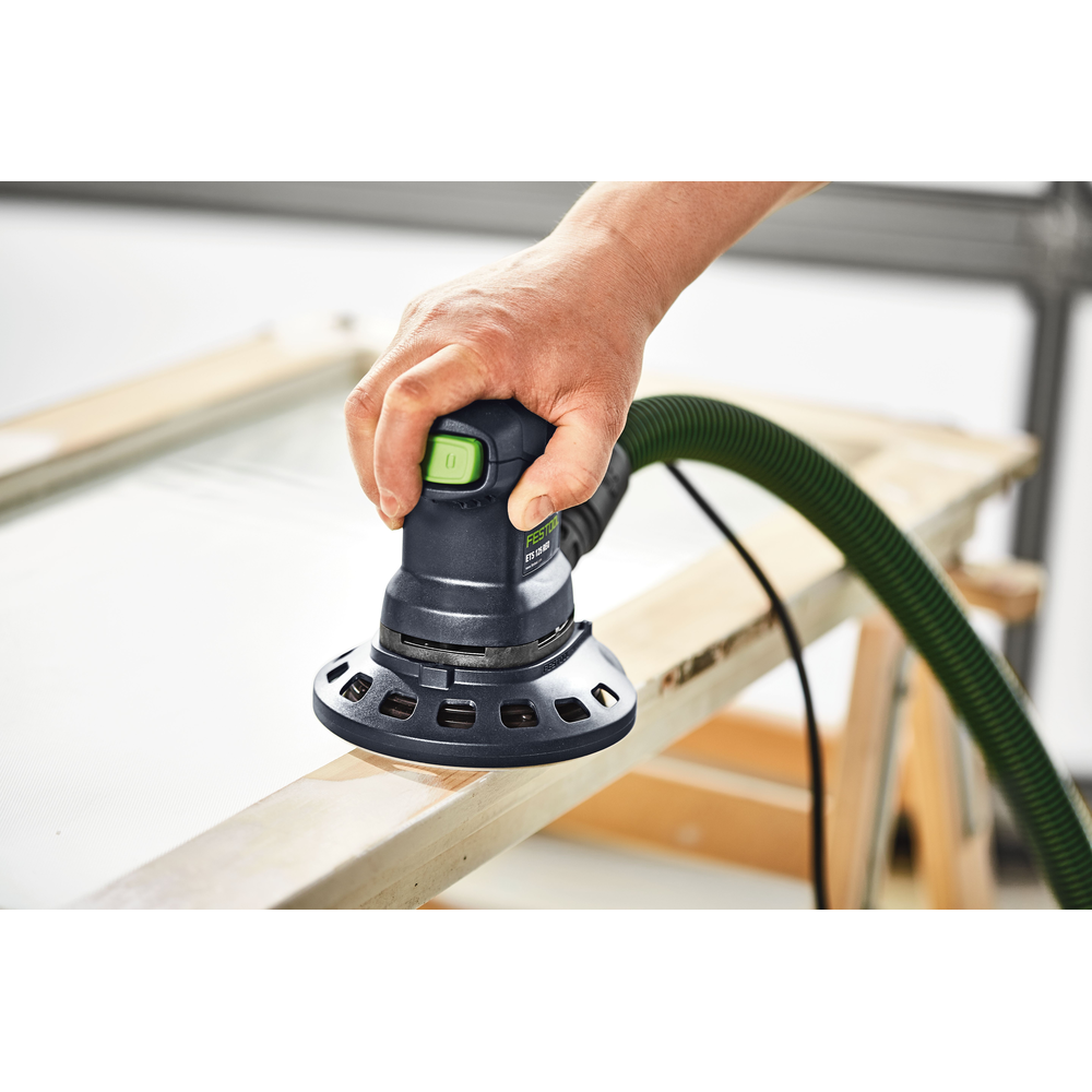 Hand holding a Festool random orbit sander connected to dust extractor sanding a white wooden frame for home improvement tasks