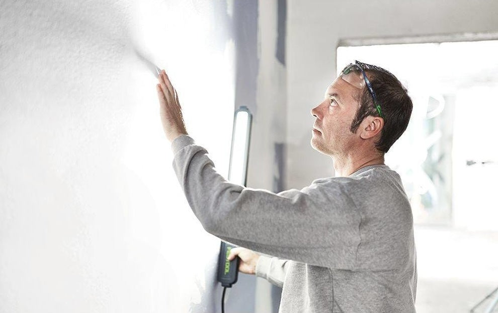 Man using handheld surface control light for inspection in home improvement and tools collection.
