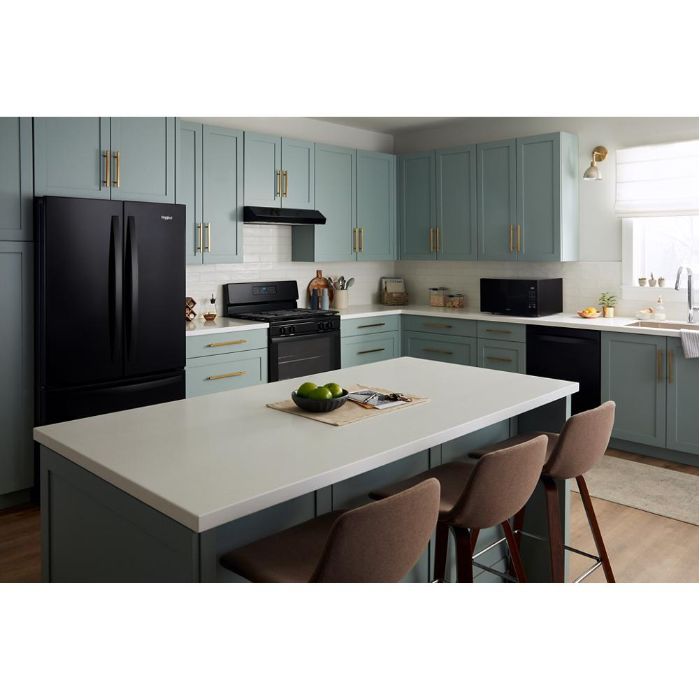 Modern kitchen with matte black appliances, green cabinetry, large island with white countertop, and brown upholstered stools