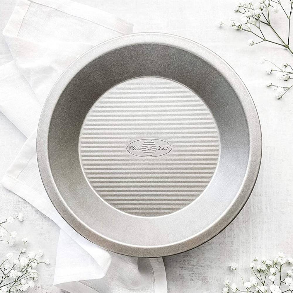 Round metal USA PAN pie pan with ribbed base for even baking on white linen and light surface