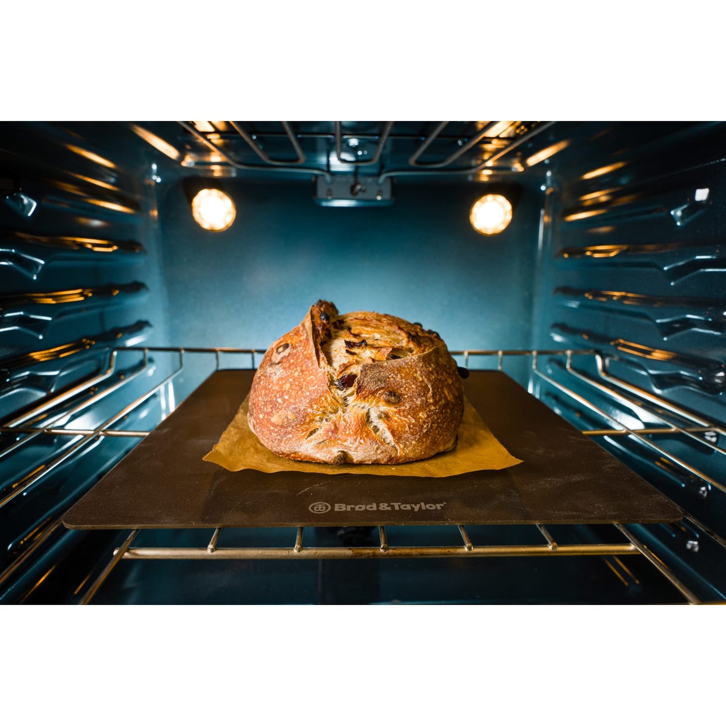 Crusty loaf baking on brown sheet on Brod & Taylor steel inside illuminated modern oven in kitchenware collection