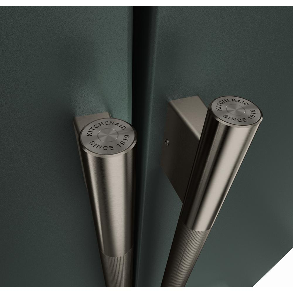 Close-up of brushed stainless steel handles with engraved KitchenAid logo on dark green French door refrigerator