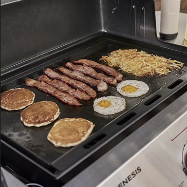 Black flat top griddle cooking pancakes, bacon, eggs, and hash browns in outdoor cooking and grill accessories collections