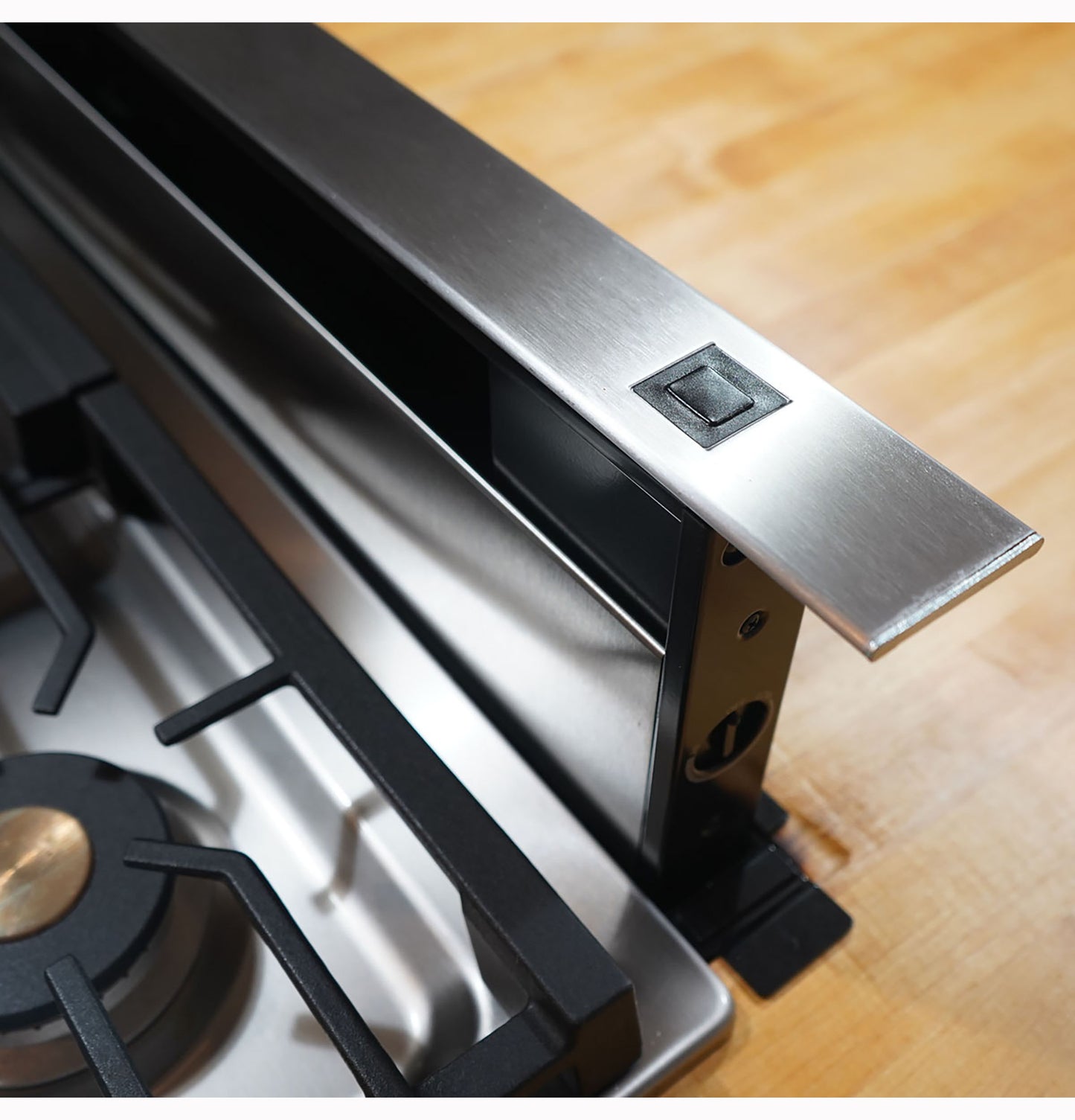 Stainless steel telescopic downdraft vent integrated beside gas cooktop in modern kitchen appliances collection