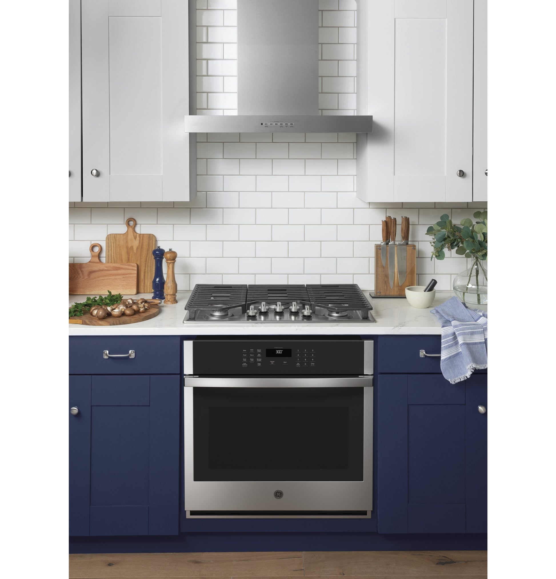 Built-in stainless steel wall oven with digital controls set in navy blue cabinetry in modern kitchen appliances collection