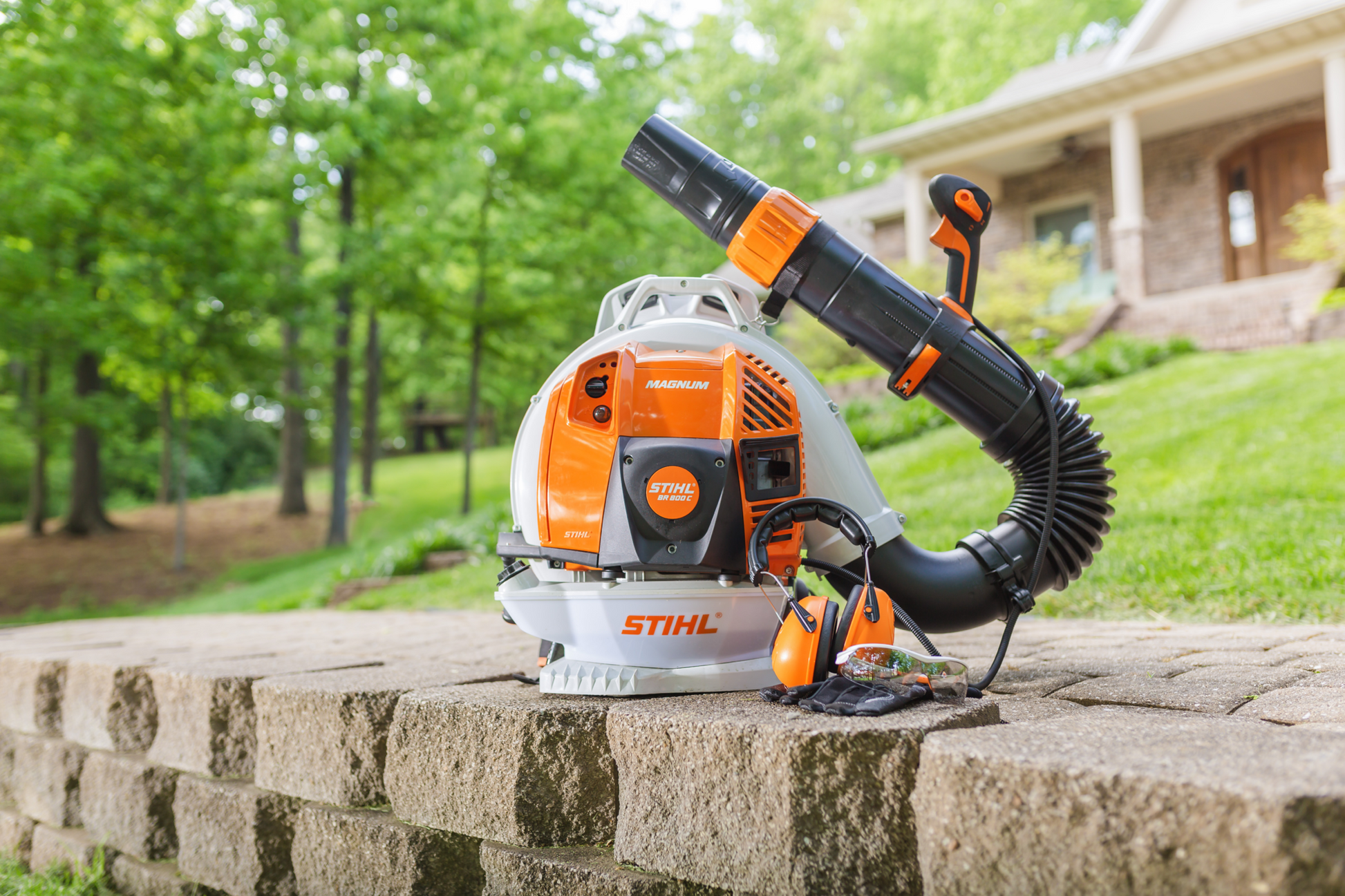 Compact orange and white backpack blower with flexible black nozzle and attached ear protection for outdoor home improvement tasks