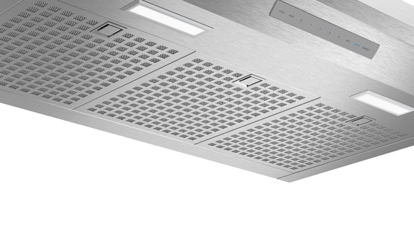 underside view of stainless steel pyramid chimney wall hood with perforated filters and LED lights for kitchen ventilation