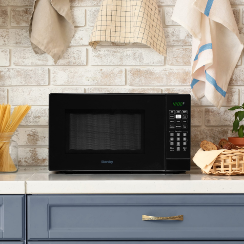 Black countertop microwave with digital control panel and green LED display on kitchen counter in home setting