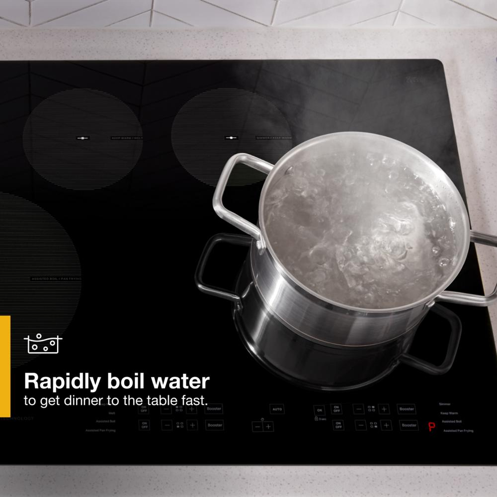 Stainless steel pot boiling water on sleek black induction cooktop from kitchenware and appliances collections.