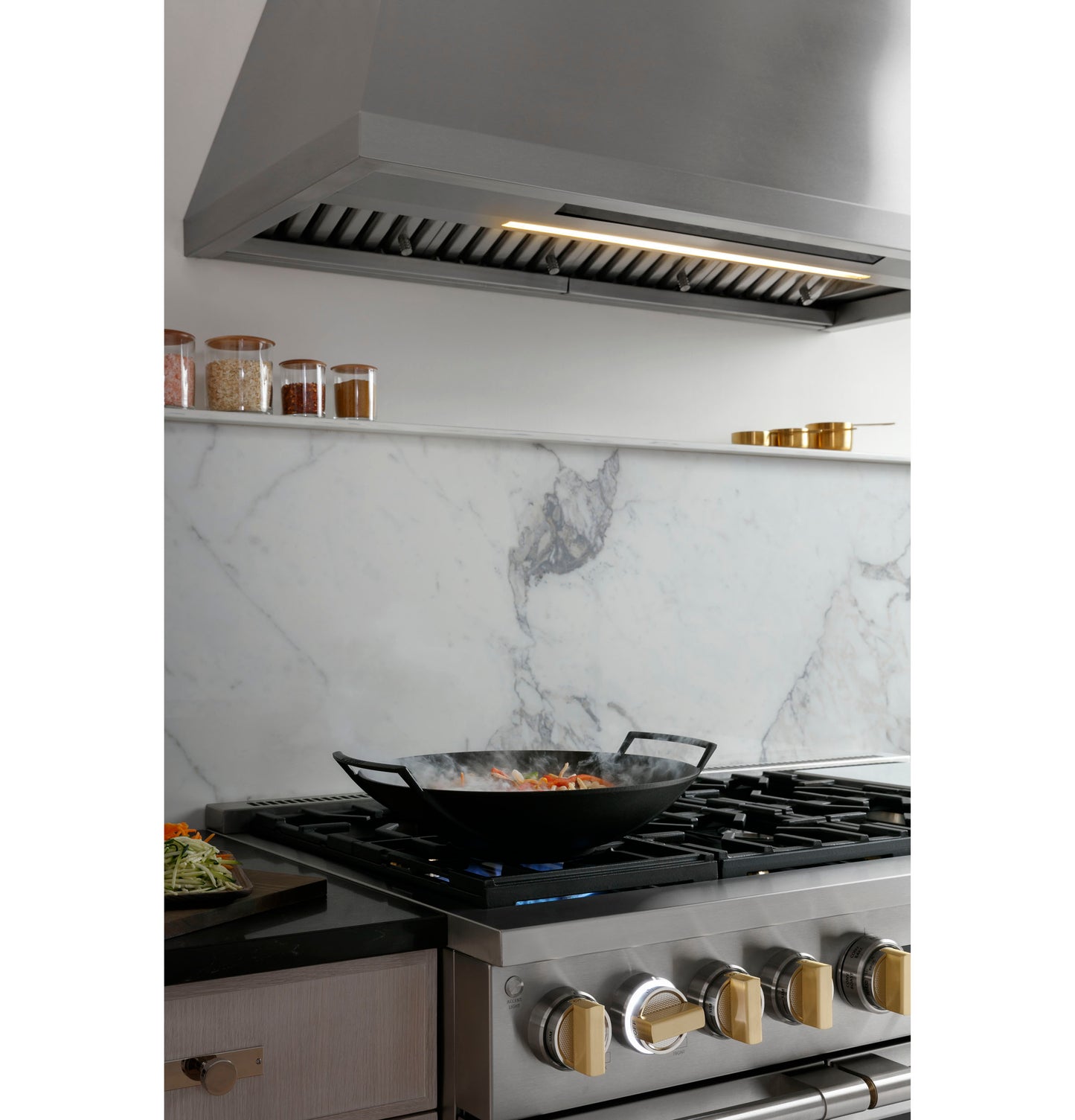 Monogram professional hood above gas cooktop with marble backsplash in modern kitchen and home improvement appliances collection