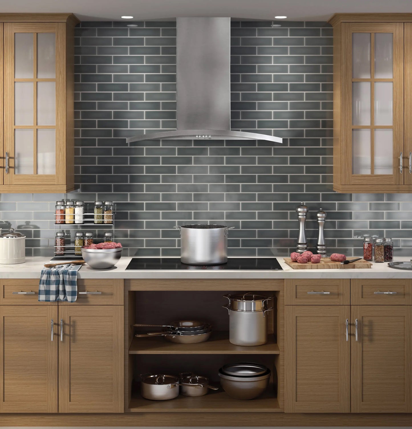 Stainless steel wall-mount chimney hood above modern cooktop with wooden cabinetry and gray subway tile backsplash