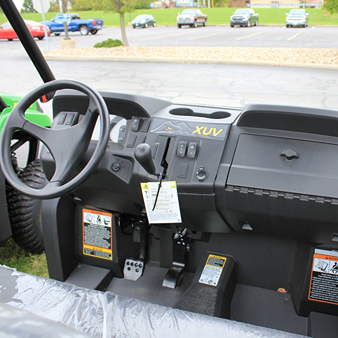 Dashboard and control panel interior view of camo mid-size crossover utility vehicle with steering wheel and pedals