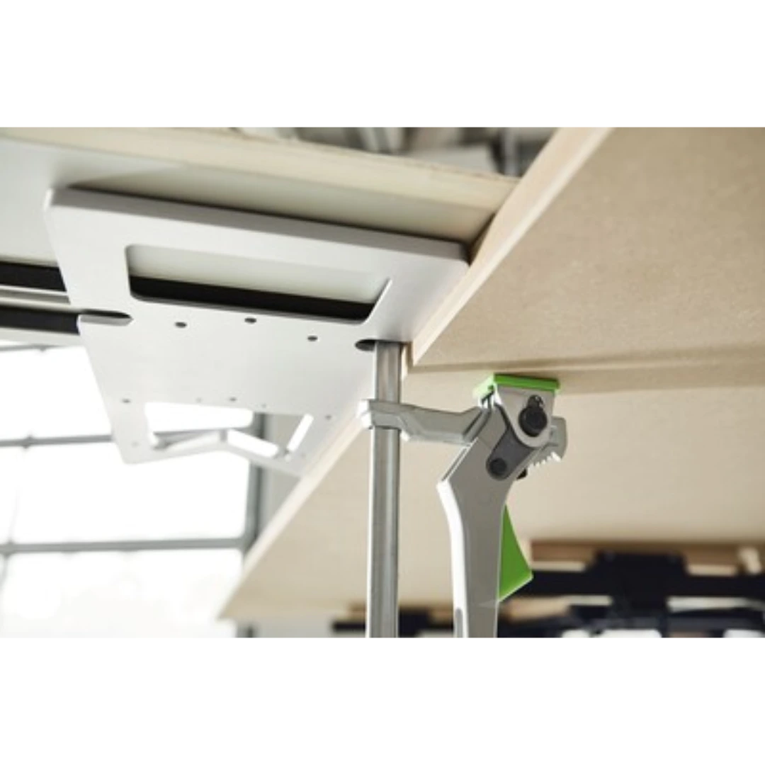 Metal quick clamp with green accents securing a workpiece on a woodworking bench in tool accessories collection