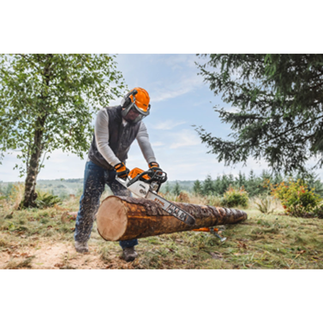 Man wearing protective gear using an orange chainsaw to cut a large log outdoors in a home improvement setting