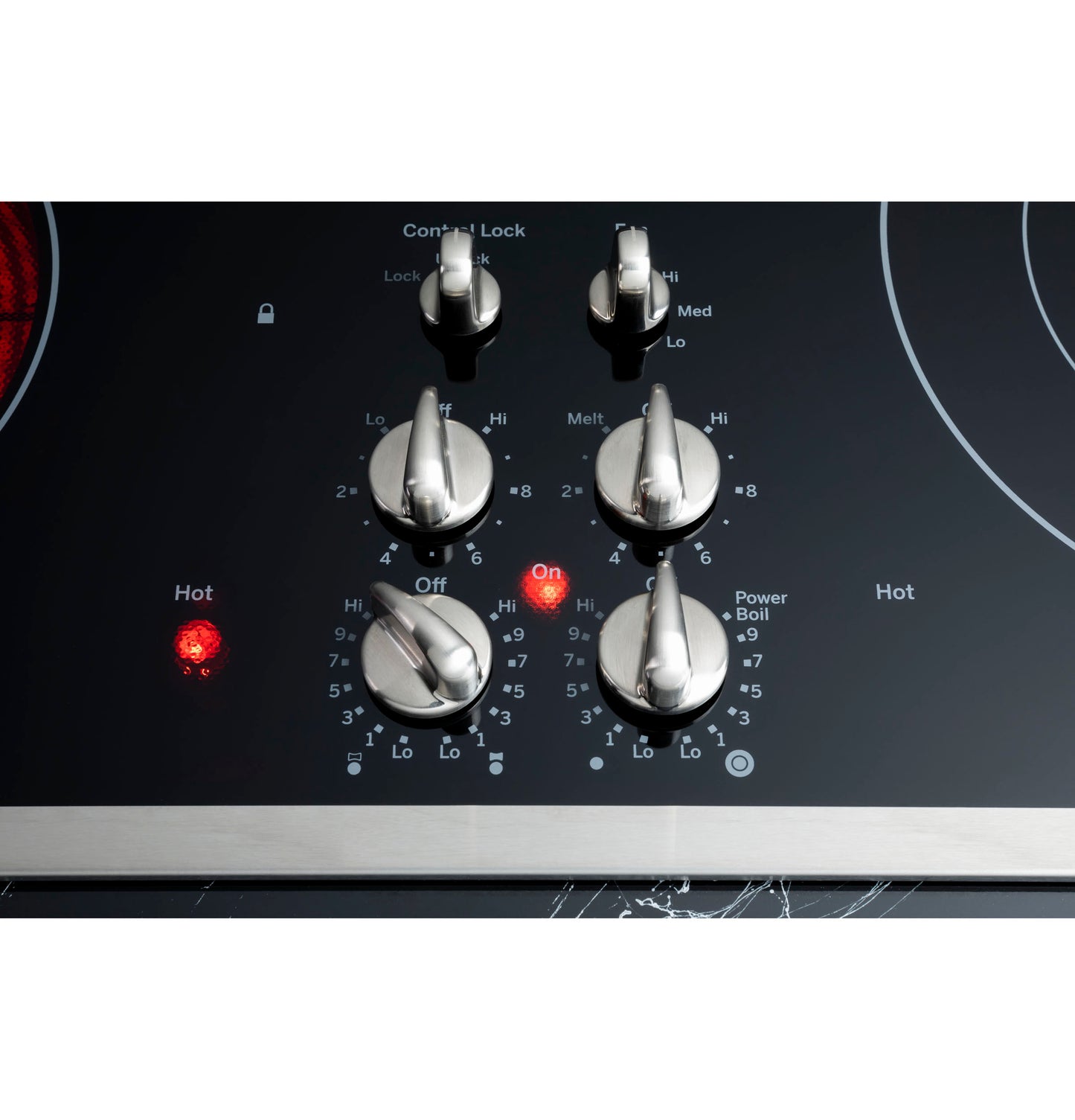 Close-up of stainless steel control knobs with illuminated indicators on black glass GE Profile cooktop in kitchen appliances collection