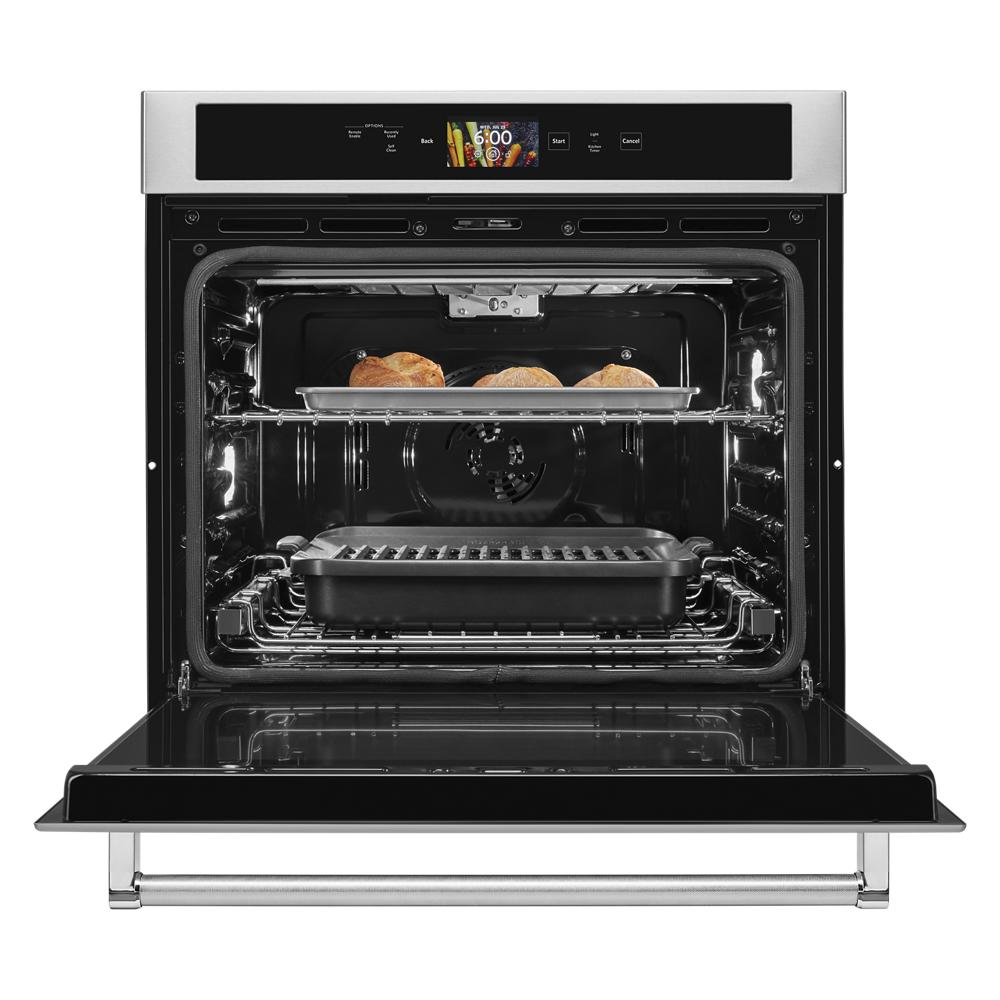 Open stainless steel smart oven with digital touchscreen, roasting bread on upper rack and grilling pan below in kitchen setting