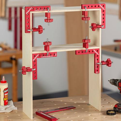 Red aluminum clamping squares with adjustable knobs securing wooden panels in woodworking and home improvement setting