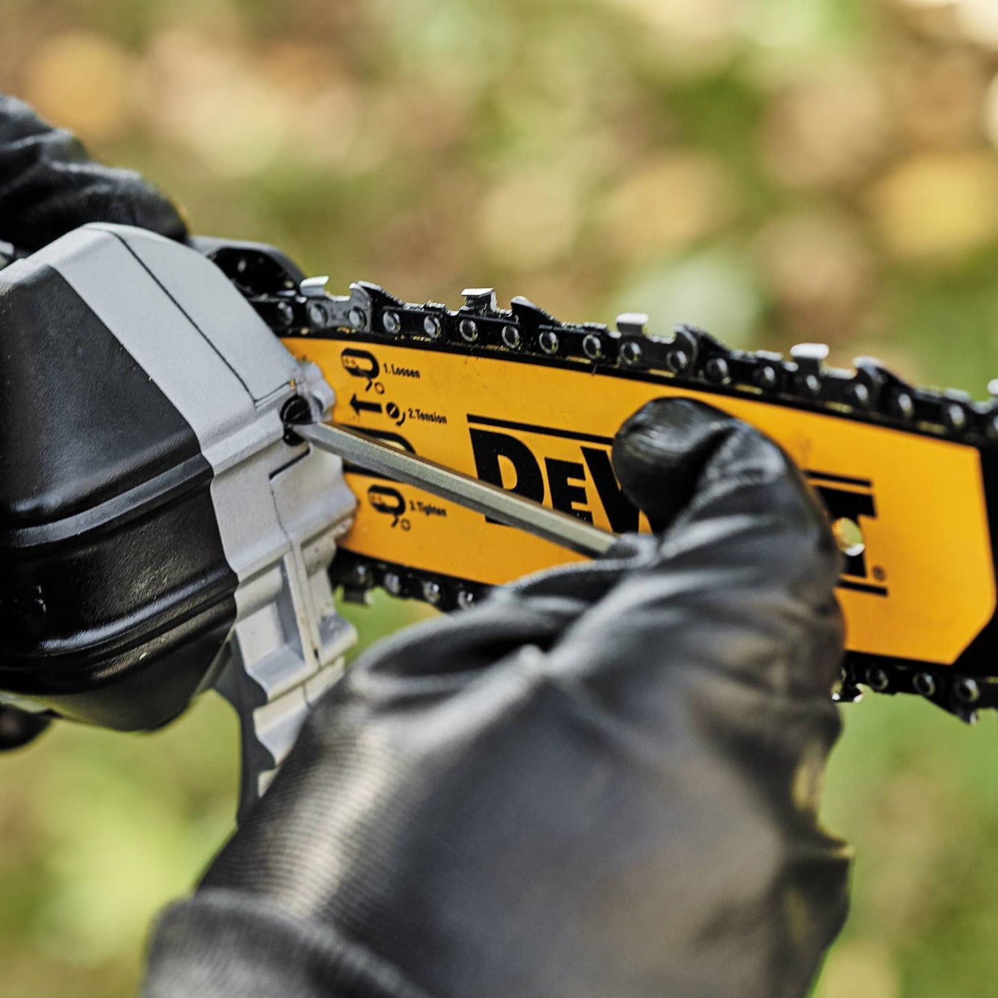 Hand in black glove tightening chain tension on yellow and black cordless pole saw for home improvement tasks