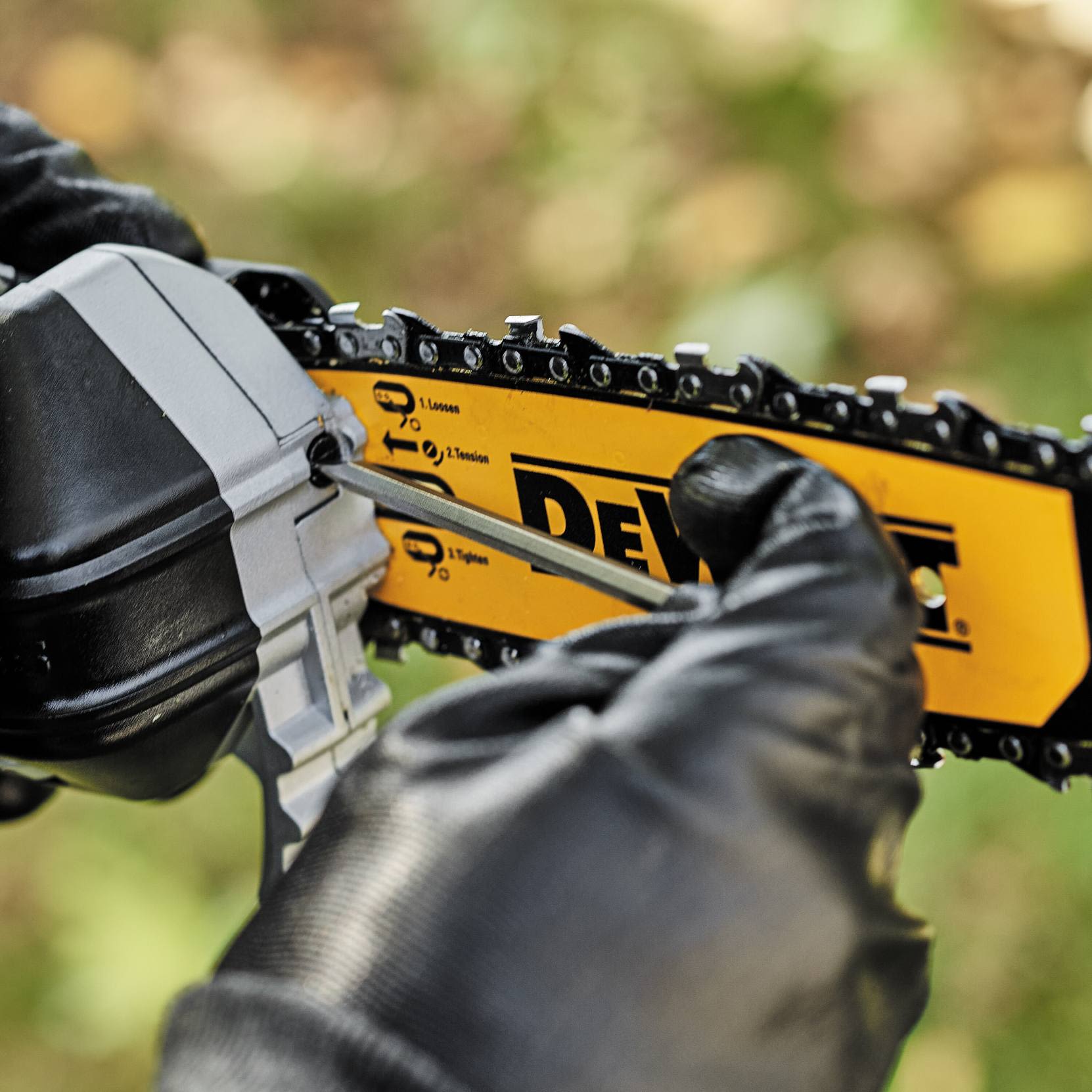 Hand in black glove tightening chain tension on yellow and black cordless pole saw for home improvement tasks