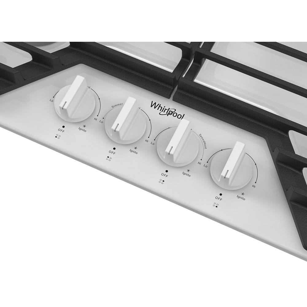 Close-up of white control panel with four knobs and black cast-iron grates on a kitchen cooktop in appliances collection