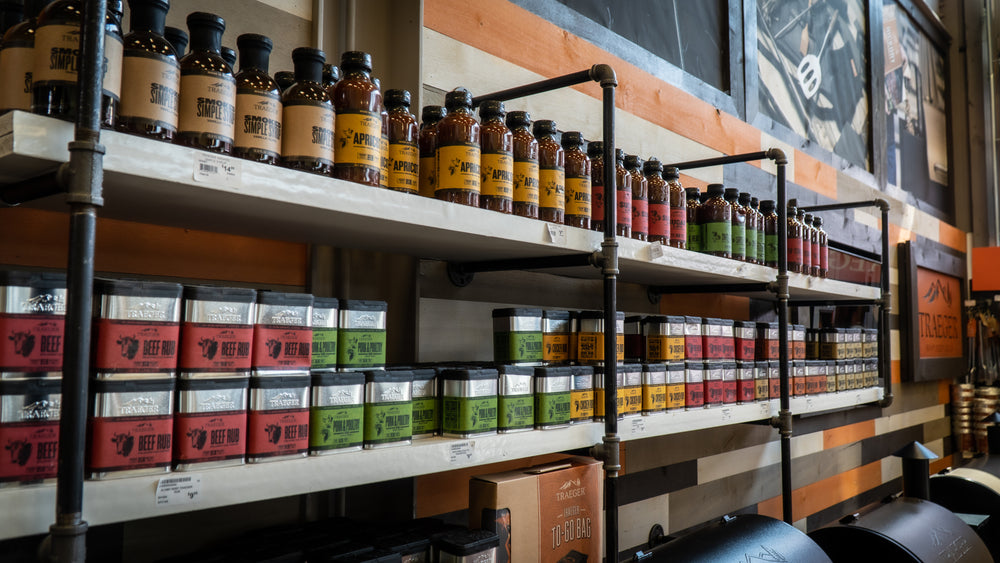 Shelves displaying various bottles and boxes of spices and seasonings arranged by color inside a store with wood and metal interior decor.