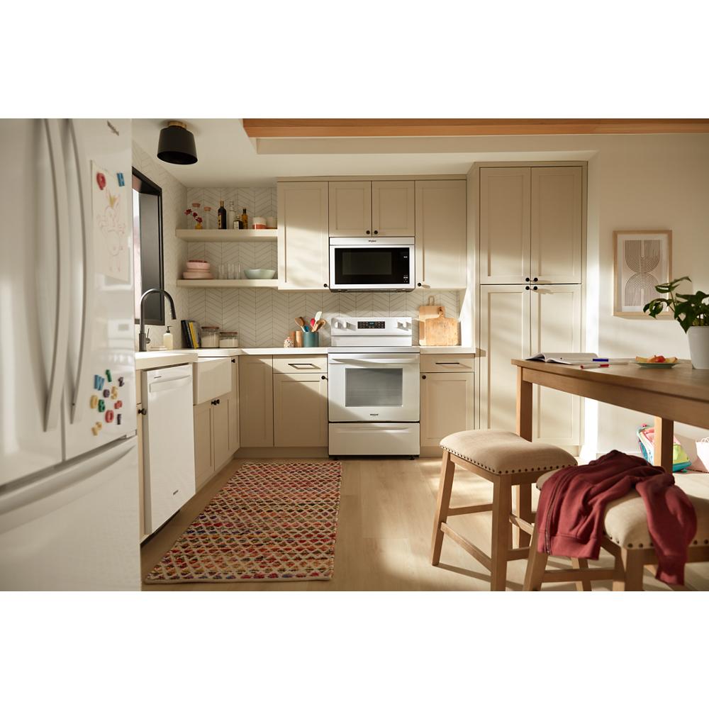 Bright kitchen with beige cabinetry, white dishwasher, stove, and microwave, wood dining table in kitchenware and appliances collection