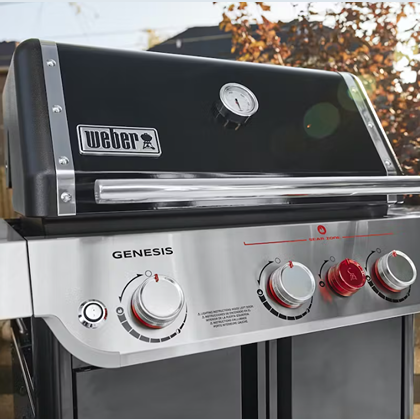 Black and stainless steel gas grill control panel with temperature gauge and three control knobs for outdoor cooking grills
