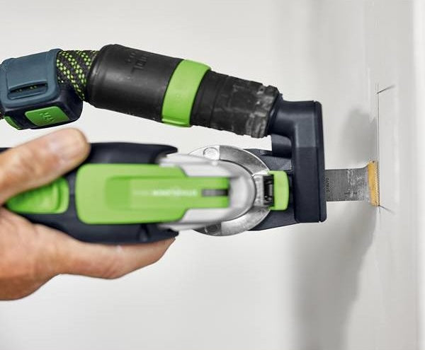 Compact oscillating tool with green accents cutting into drywall for precise home improvement projects