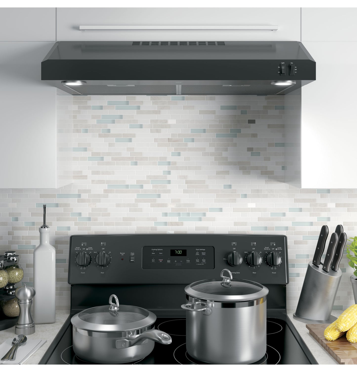 Black under cabinet range hood with dual lights and control switches above black electric stove in kitchen appliances collection