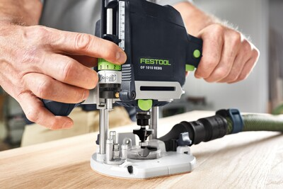 Hands setting depth adjustment on a Festool router with dust extraction during a home improvement woodworking task